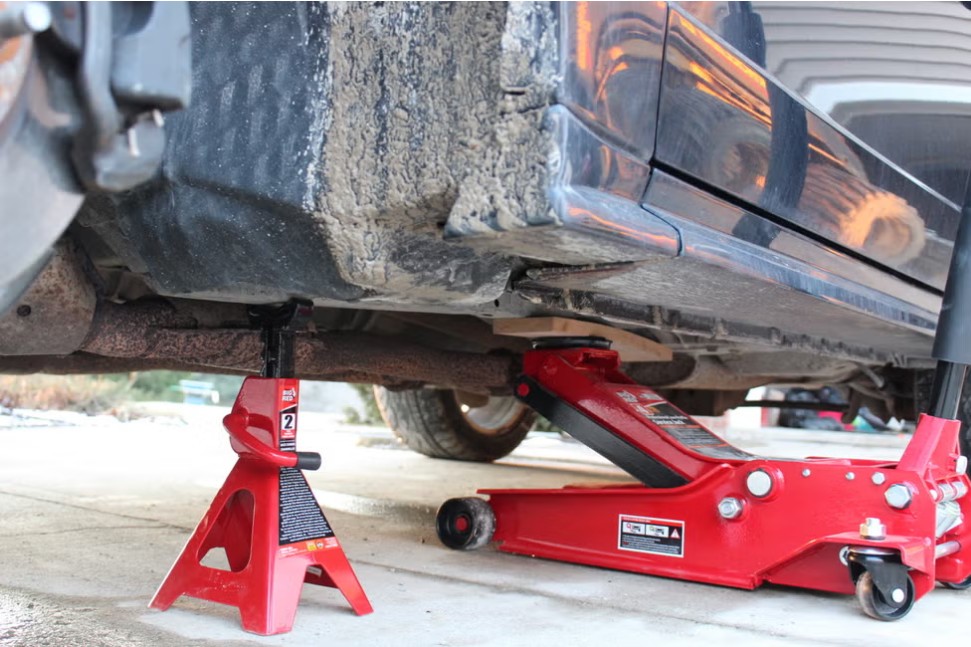 A 2 ton jack stand supporting a truck alongside a hydraulic floor jack