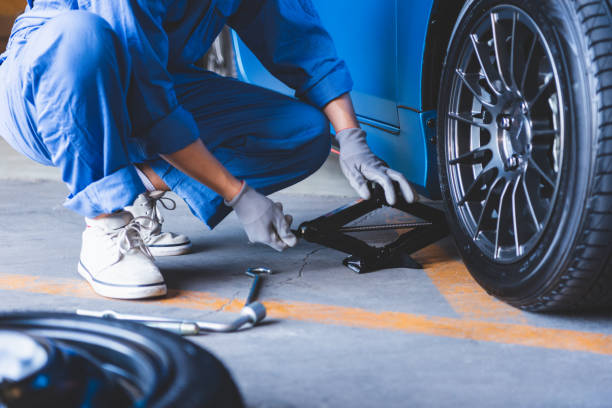 A scissor jack in use on pavement — not allowed